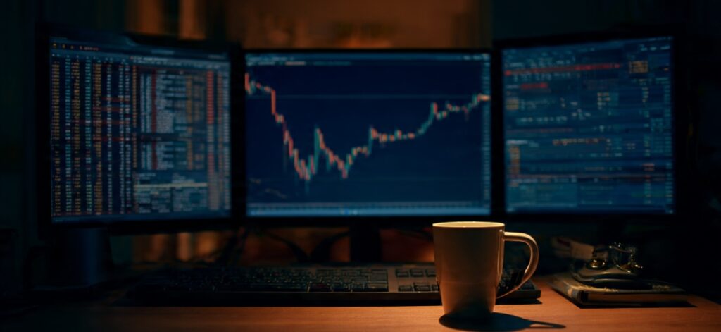 Trader at night showing the warning signs of overtrading on multiple charts
